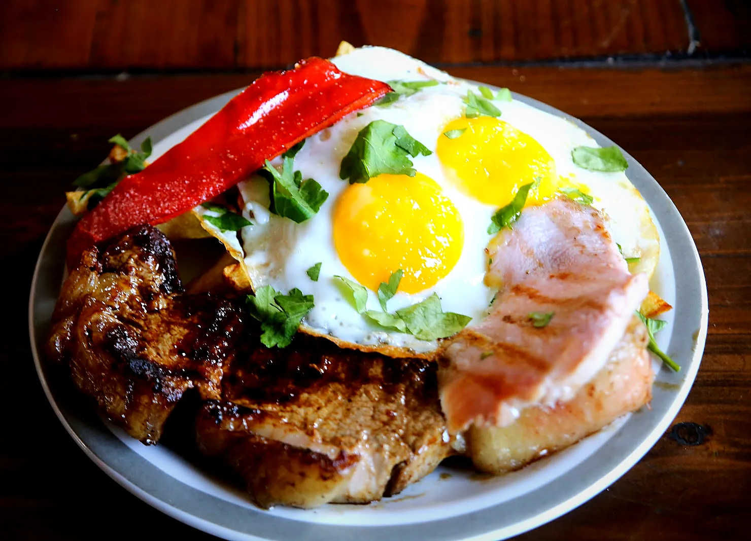 Bife de chorizo con dos huevos fritos, panceta y morrón asado