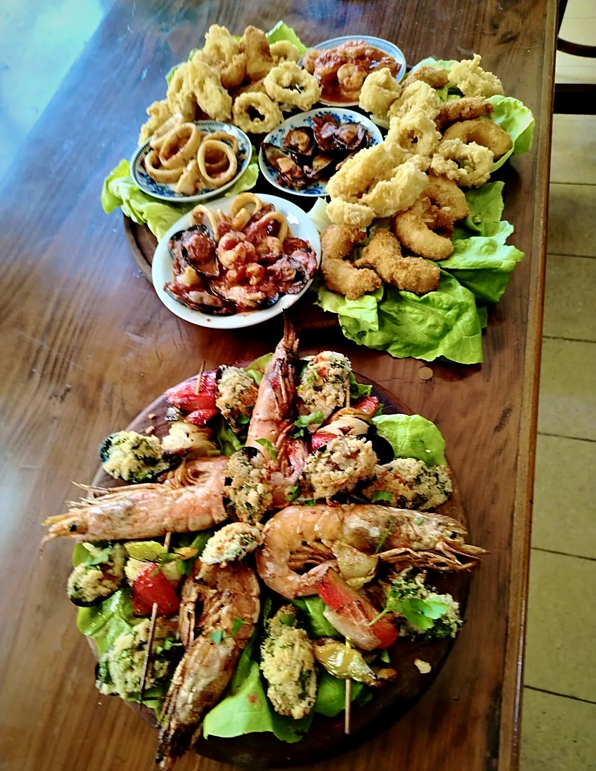 Rabas, langostinos y cazuelitas de mariscos sobre una mesa de madera